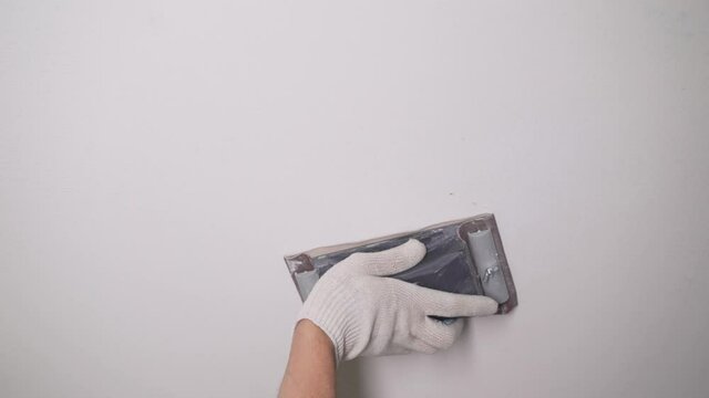 Cleaning the ceiling for painting. Cleans white ceilings with sandpaper. Close-up of a hand sanding the ceiling with sandpaper. Sanding the walls with sandpaper.