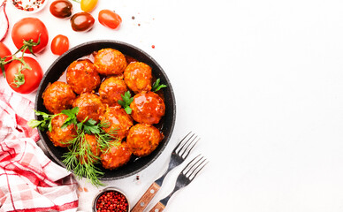 Meatballs with spicy tomato sauce in frying pan on white kitchen table. Top View