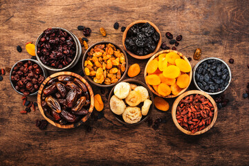 Healthy food snack: sun dried organic mix of dried fruits: apricots, figs, raisins, dates, and other on wooden table, top view