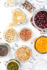 Plastic free storage and cooking concept. Various organic superfoods, beans, grains, cereals, legumes, seeds in reusable cans and jars. White table. Zero waste and sustanable lifestyle