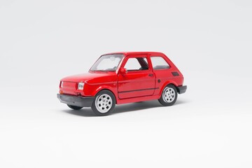Maluch samochód zabawka koloru czerwonego stojący bokiem na białym tle  - obrazy, fototapety, plakaty
