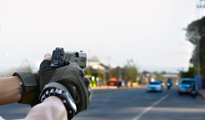 Automatic 9mm black pistol holding in hands, aiming to shooting target and ready to shoot, concept for robbery, safety, security, bodyguard and killer on the road. Selective focus on pistol and hands.
