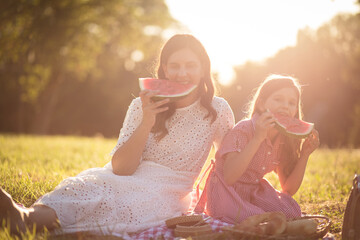 Obraz premium Mother and daughter eating watermelon in nature. Portrait of mother daughter.