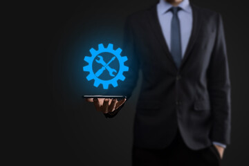 Businessman holding gear icon with tools.Gearing.Concept of target focus digital diagram,graph interfaces,virtual UI screen,connections netwoork.