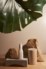 White ceramic opaque bottle on a beige background without labels on natural podium, stones and podium for your product demonstration with tropical plant frame