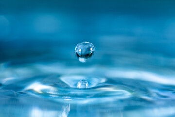 water drop splash in a glass blue colored shot of water that is dripping and reflecting water.