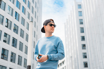 Young free beautiful fashionable hipster guy walking down the street, wearing a cap sunglasses, urban style