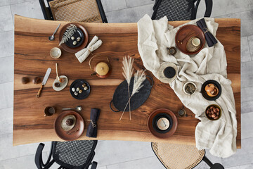 Stylish interior design of dining room with wooden walnut table, retro chairs, tableware, plates,...