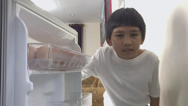 Asian boy was disappointed and sad when opening the refrigerator and it was empty