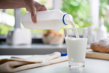 Pouring milk into glass in the kitchen..