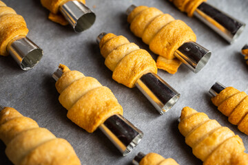 Lots of sweet home made confectionery tubes prepared to be filled with cream. Photo taken under...