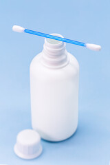 hydrogen peroxide, in white plastic bottle, with cotton swab and isolated blue background, medicine concept, medicine for wounds and small cuts