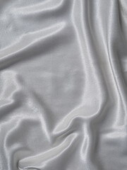 White satin background with folds and shadows. Light shiny rippled silk texture website...