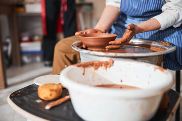 Young ceramist taking bowl from pottery wheel