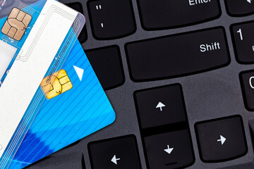 Credit cards stacked on a black laptop keyboard. Photo taken under artificial, soft light