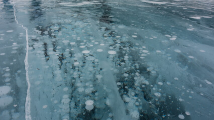 Obraz premium Ice surface. Close-up. Full screen. Cracks and columns of frozen methane gas bubbles are visible. Lake Baikal in winter.