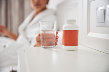 Orange pill jar and water on the desk in bedroom