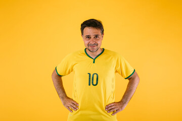 Brazilian soccer fan in yellow shirt, poses with arms on waist