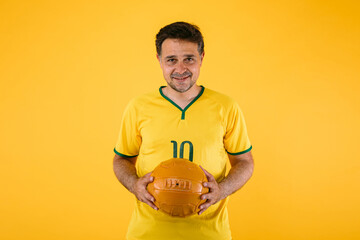 Brazilian soccer fan with red jersey and a retro ball in his hands