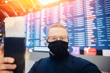 Concept new normal travel on airplane. Traveller young man is wearing protective mask in airport after covid pandemic, social distancing