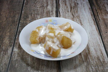Pile of sweet potato or Tapioca in syrup seasoning with coconut cream serving on the plate. Famous ancient Thai dessert in Asia restaurant.