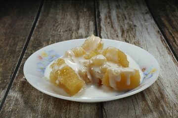 Pile of sweet potato or Tapioca in syrup seasoning with coconut cream serving on the plate. Famous ancient Thai dessert in Asia restaurant.