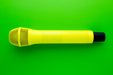 Yellow professional vocal wireless microphone on green background.
