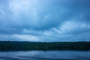 Shore with trees growing on it. Above blue sky with barely visible clouds. Nordic style. There is space for text.