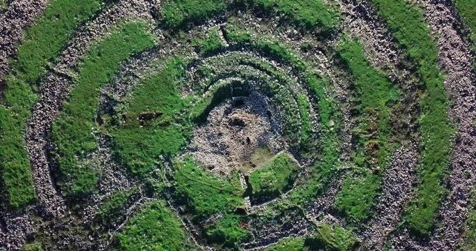 Aerial Top Upward Shot Of Rujm El-Hiri Monument On Sunny Day, Drone Flying Over Popular Landscape - Golan, Israel