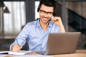 Joyful confident young caucasian man wearing glasses and headset, freelancer, office worker or...