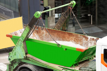 container with cement is deposited by construction truck on city street