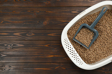 Cat litter tray with filler and scoop on wooden background, top view. Space for text