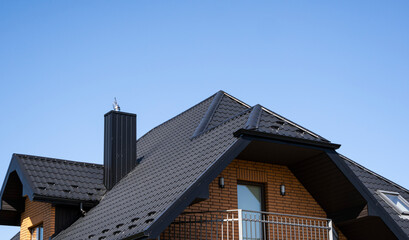 Brown corrugated metal profile roof installed on a modern house. The roof of corrugated sheet. Roofing of metal profile wavy shape. Modern roof made of metal. Metal roofing.