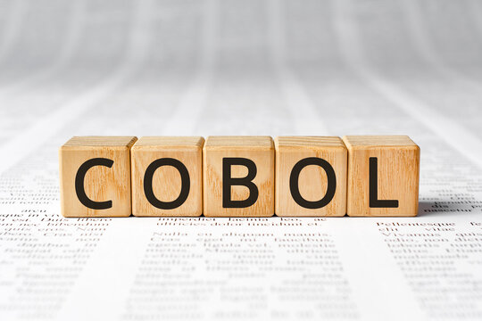 Cobol - word wooden blocks with letters, Cobol COmmon Business Oriented Language concept, paper background newspaper text