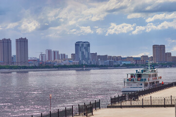 Pleasure boat on the pier of the embankment of Blagoveshchensk. Across the Amur River, the city of Heihe.