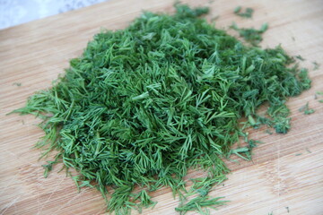 Chopped dill on the wooden cutting board, close-up