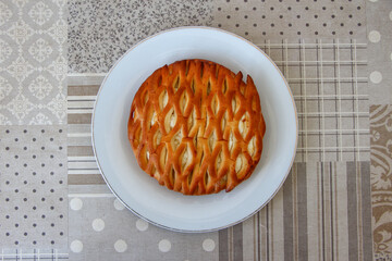 Wicker bun with cottage cheese on a plate, top view