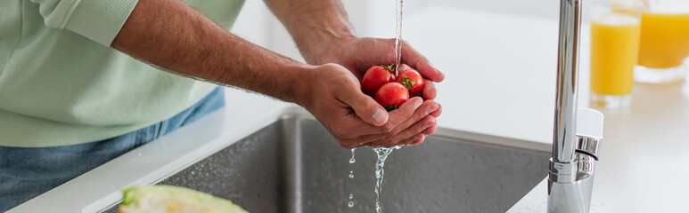 partial view of man washing cheery tomatoes in kitchen, banner