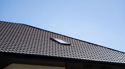 Brown corrugated metal profile roof installed on a modern house. The roof of corrugated sheet. Roofing of metal profile wavy shape. Modern roof made of metal. Metal roofing.