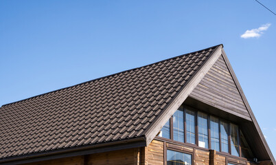 Brown corrugated metal profile roof installed on a modern house. The roof of corrugated sheet. Roofing of metal profile wavy shape. Modern roof made of metal. Metal roofing.