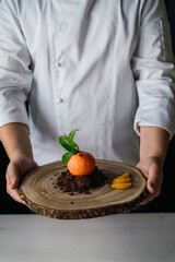 Pastelería con forma de mandarina sobre galletas de chocolate se desmorona sobre una tabla de madera
