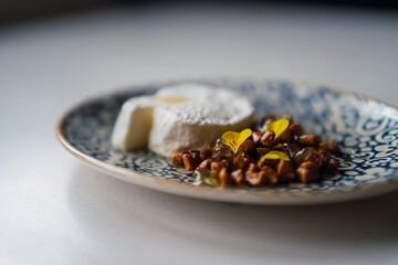 plano de un pequeño pastel blanco cortado con nueces y flores comestibles en un plato sobre la mesa