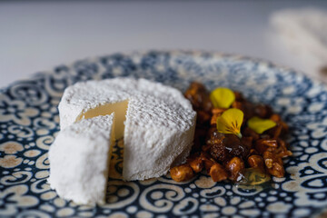 plano de un pequeño pastel blanco cortado con nueces y flores comestibles en un plato sobre la mesa
