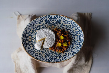 plano de un pequeño pastel blanco cortado con nueces y flores comestibles en un plato sobre la mesa