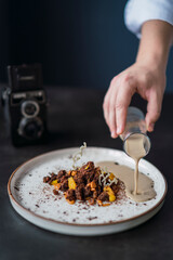 Postre de chocolate con salsa de café y decoración de una cámara antigua de fondo