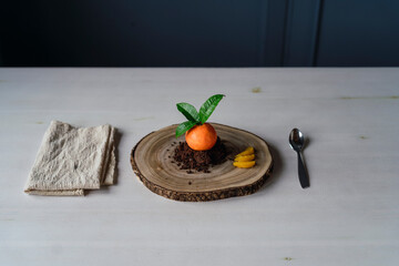 Pasteler&iacute;a con forma de mandarina en galletas de chocolate sobre una tabla de madera sobre la mesa