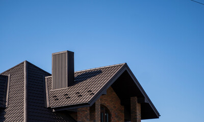 Brown corrugated metal profile roof installed on a modern house. The roof of corrugated sheet. Roofing of metal profile wavy shape. Modern roof made of metal. Metal roofing.
