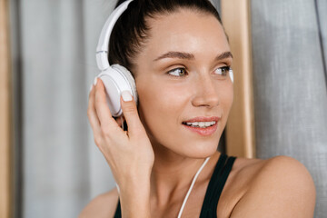 Naklejka premium White brunette woman listening music with headphones at home