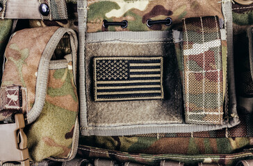 Close-up photo of multi camouflaged soldier vest pouches system with american flag patch..