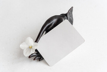 Decorative black holder in mudra hand shape with gentle fresh flower and blank business card on...